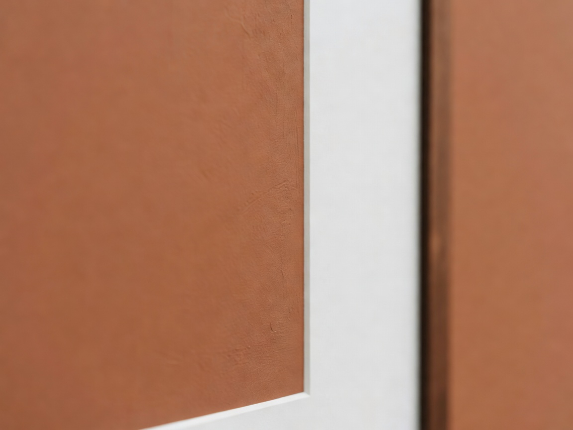 Shallow-focus detail of a clay-coloured chalk paint finish meeting the white mat edge of a display